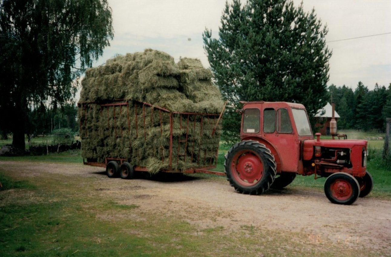 Traktor med hölass på gården
